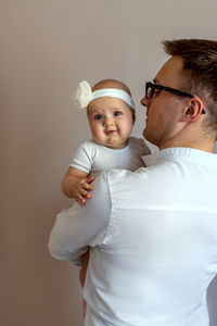 Father holding daughter against beige background