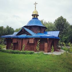 Gazebo on field by building against sky