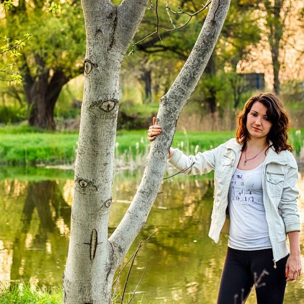 tree, tree trunk, lifestyles, leisure activity, casual clothing, water, young adult, person, standing, forest, front view, three quarter length, looking at camera, nature, focus on foreground, day, lake, portrait