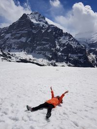 Girl with arms raised lying on snowcapped mountain