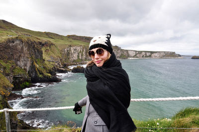 Woman wearing scarf standing at observation point against sea