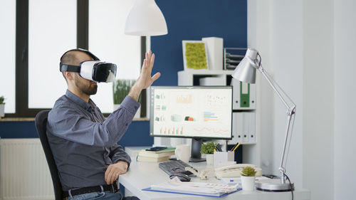 Young businessman wearing virtual reality simulator gesturing with hand