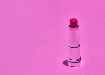 Close-up of glass bottle against pink background