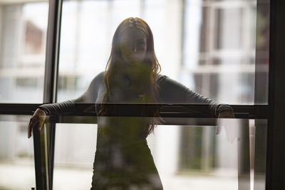 Portrait of thoughtful young woman standing by windows