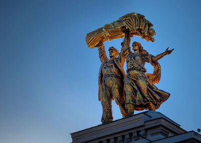 Low angle view of angel statue against clear blue sky