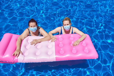 Two women bathe in a pool with a mask.