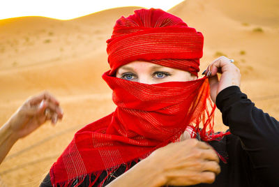 Portrait of woman wearing red headscarf at desert