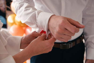 Cropped photo of female hands fasten the button on her husband formal shirt