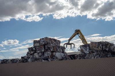 Low angle view of machinery on rock against sky