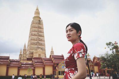 Beautiful woman standing near temple against sky