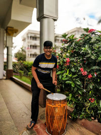 Portrait of young man standing against potted plants