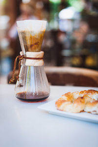 Close-up of coffee filter with croissant on table