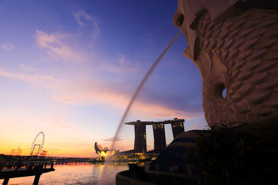 Silhouette built structure by sea against sky during sunset