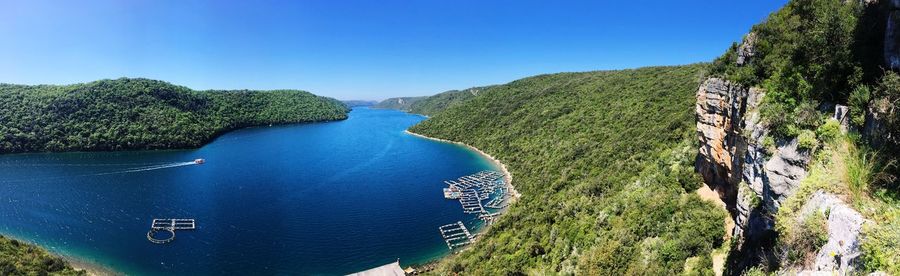 High angle view of sea and trees against clear blue sky
