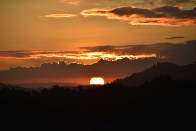 Scenic view of silhouette mountains against romantic sky at sunset