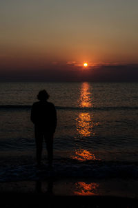 Silhouette man standing on beach against sky during sunset