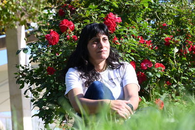 Portrait of young woman sitting by plants