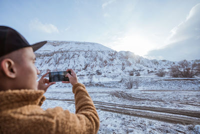 Young man photographing against sky