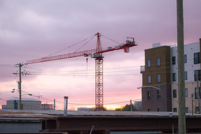 Low angle view of crane at construction site against sky during sunset