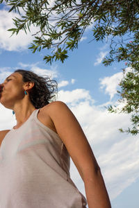 Low angle view of young woman against sky