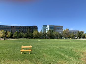 Park by buildings against clear blue sky