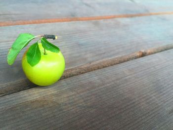 High angle view of green plum on hardwood floor