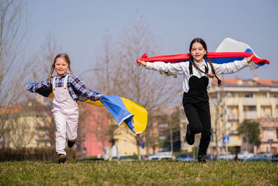 Full length girls holding flags on grass