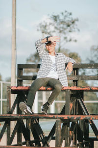 Full length of young man sitting on railing