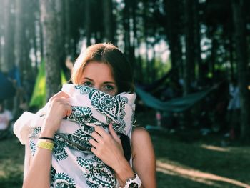 Portrait of young woman standing against trees
