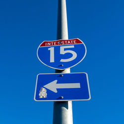 Low angle view of road sign against clear blue sky