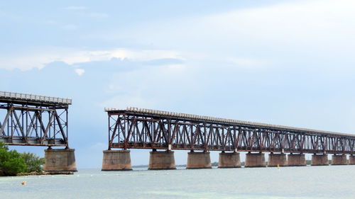 Old bridge over sea against cloudy sky