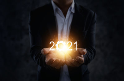 Midsection of man holding illuminated candles