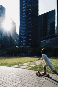 Side view of woman walking against modern buildings in city