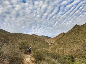 Rear view of man on mountain against sky