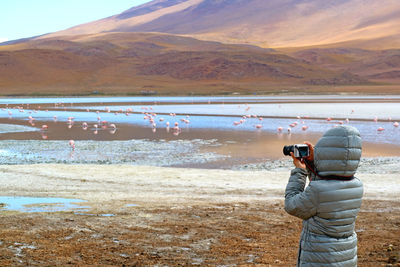 Rear view of man photographing at camera