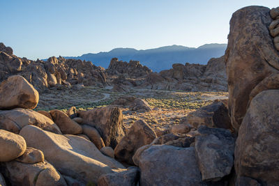 Scenic view of rocks in desert and mountains against clear sky