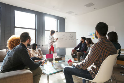 Businesswoman explaining on whiteboard to colleagues during meeting in office