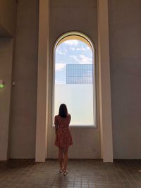 Rear view of woman standing against window in building