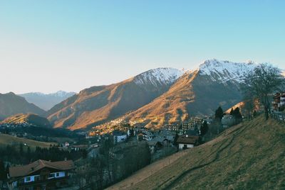 Panoramic view of townscape by mountains against clear sky