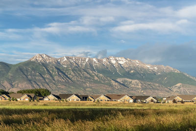 Houses on field by mountain against sky