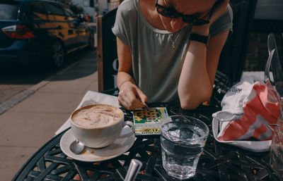 Midsection of woman holding coffee cup on table