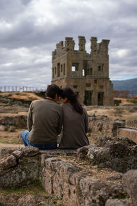 Rear view of people at historical building against cloudy sky