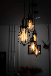 Close-up of illuminated light bulb hanging on wall at home