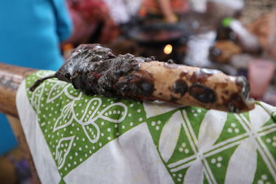 Close-up of hand holding meat on barbecue grill