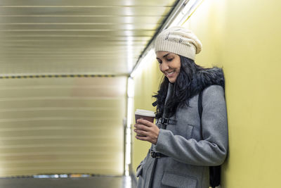 Young latina standing on the subway with her coffee to go