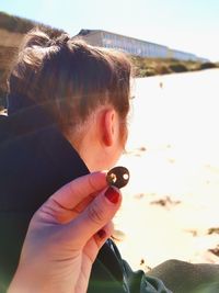 Close-up portrait of woman holding sunglasses at beach