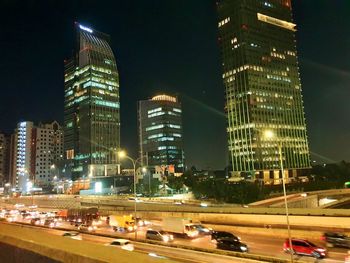 Illuminated modern buildings in city against sky at night