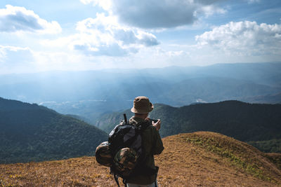 Rear view of man standing on mountain against sky