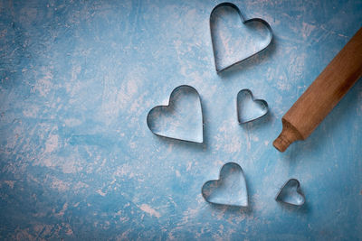Directly above shot of heart shape pastry cutters by rolling pin on table
