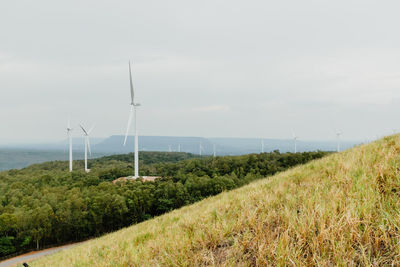 Wind turbines on field against sky